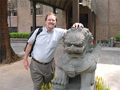 Man standing next to lion sculpture.