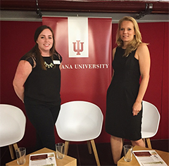 Two women standing in front of a banner.